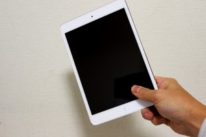 Foto af en hånd, der holder en iPad mini med hvid kant